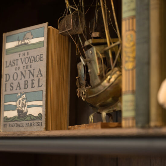 Close-up of bookshelf at The White Sheep café in Naperville with vintage book, model ship, and small sheep figurine.