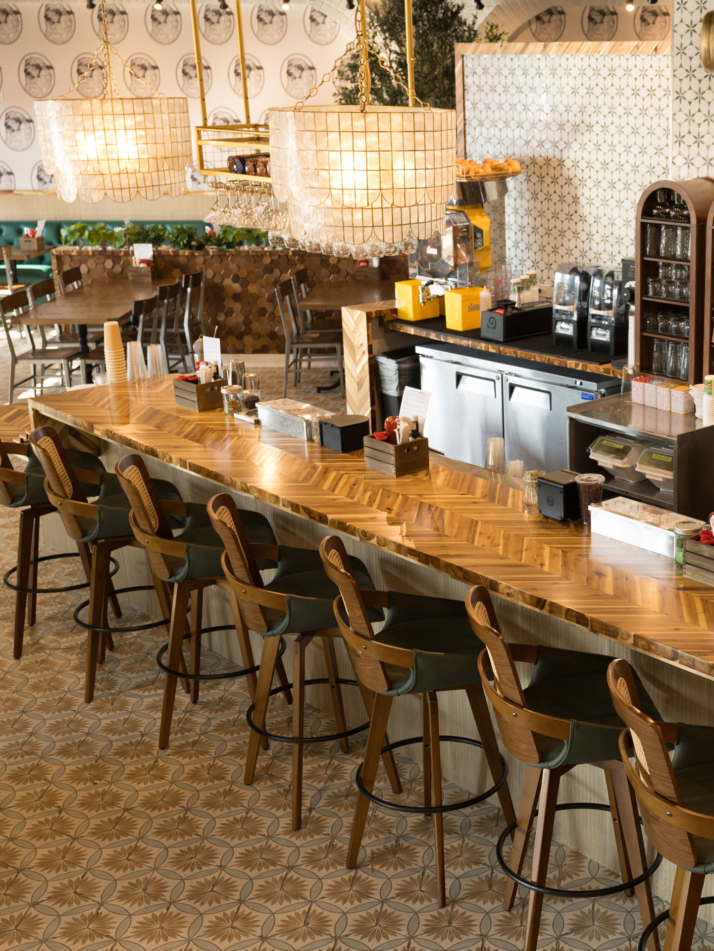 Bar counter at The White Sheep café in Naperville with wooden stools, pendant lights, and patterned tile flooring.