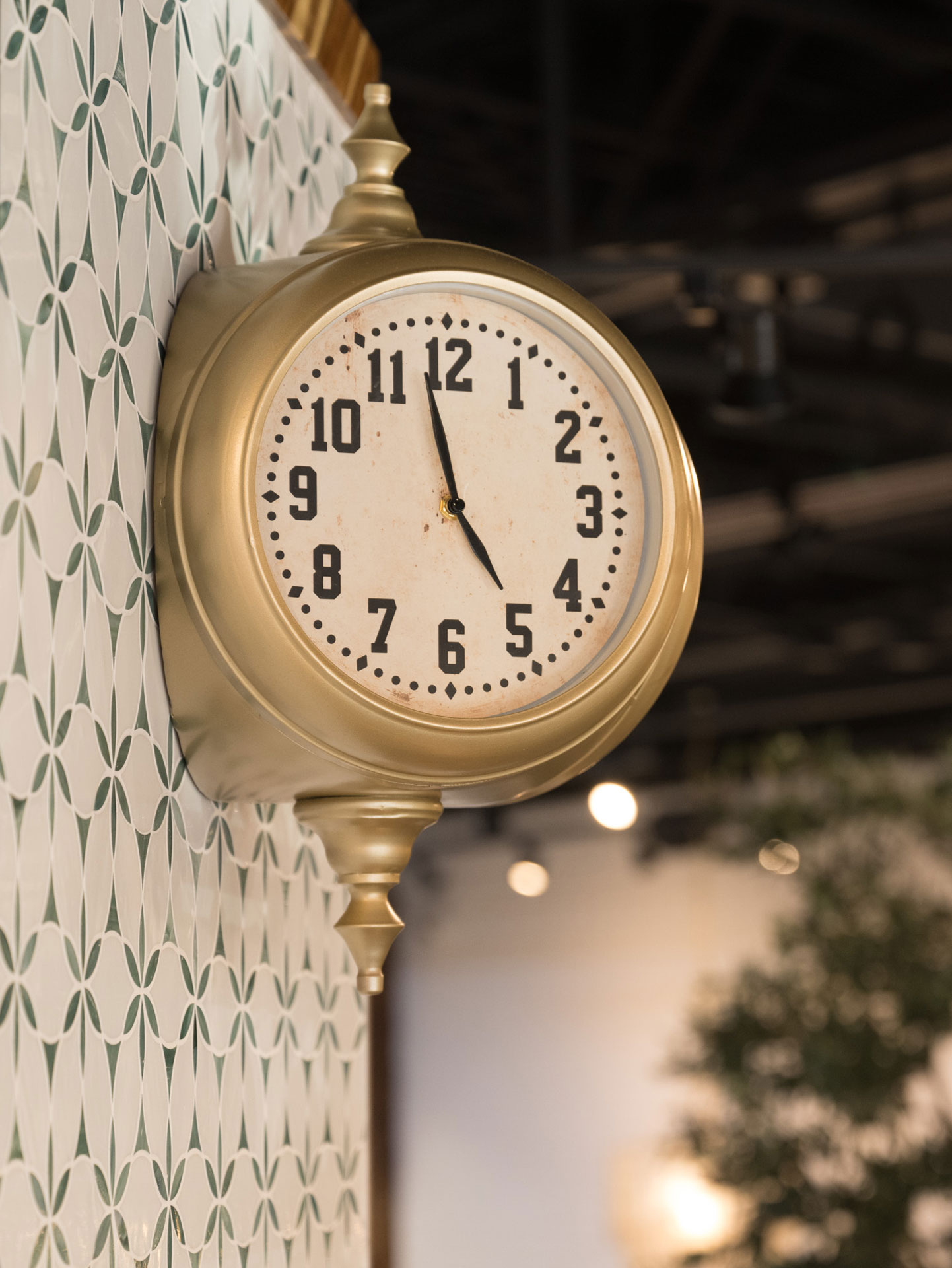 Vintage-style gold clock on patterned tile wall at The White Sheep café in Naperville.